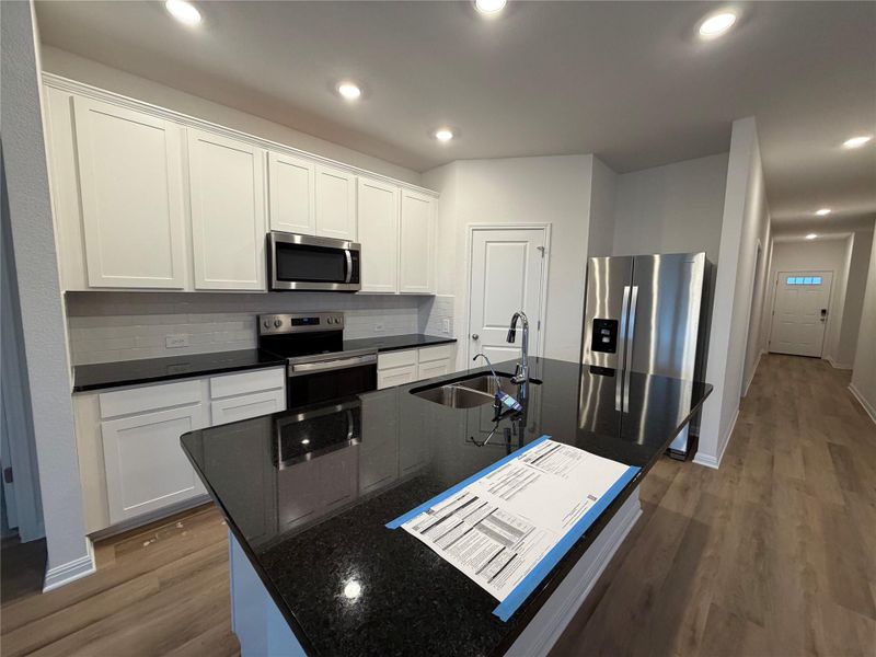 Kitchen with stainless steel appliances, white cabinetry, dark wood-style flooring, tasteful backsplash, and recessed lighting Kitchen with stainless steel appliances, white cabinetry, dark wood-style flooring, tasteful backsplash, and recessed lighting