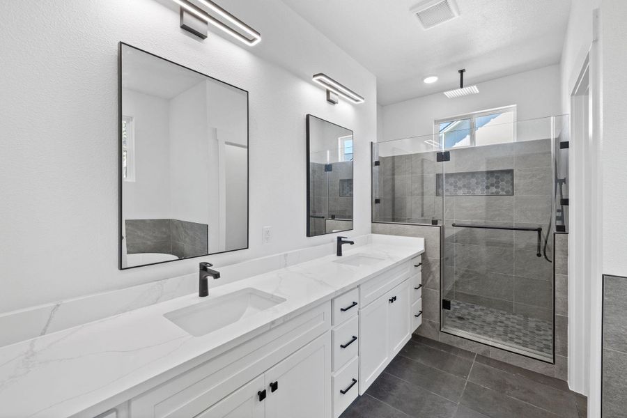 A contemporary primary bathroom features a dual vanity and a spacious glass-enclosed shower with stylish tile work. A contemporary primary bathroom features a dual vanity and a spacious glass-enclosed shower with stylish tile work.