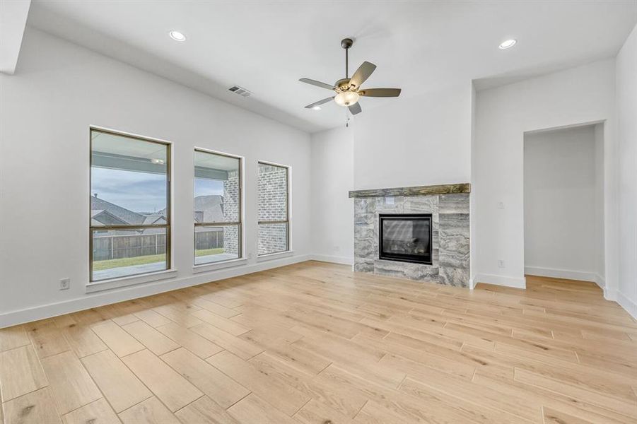 Unfurnished living room featuring a ceiling fan, wood finish floors, recessed lighting, and a glass covered fireplace