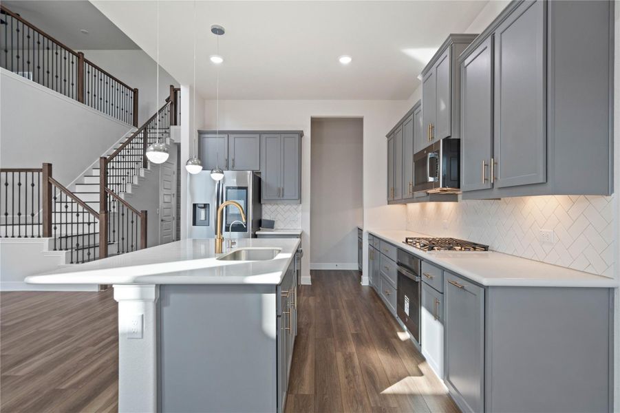 Gleaming stone countertops and a generous island anchor this modern kitchen with warm wood flooring.