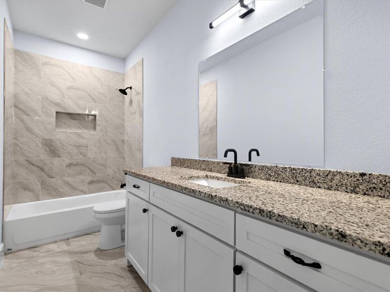 Bathroom featuring vanity, shower / bath combination, and marble look tiles