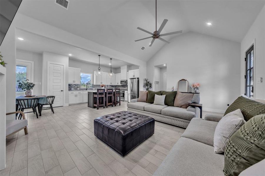 Open-concept living space featuring wood-finish flooring, vaulted ceilings, recessed lighting, and a modern ceiling fan