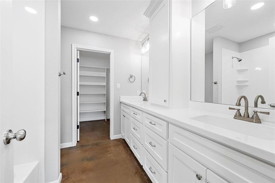 Full bath featuring double vanity, a sink, a shower, and finished concrete floors