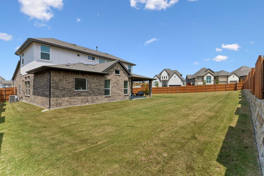 An expansive green lawn spans the fully fenced backyard of this brick-accented home.