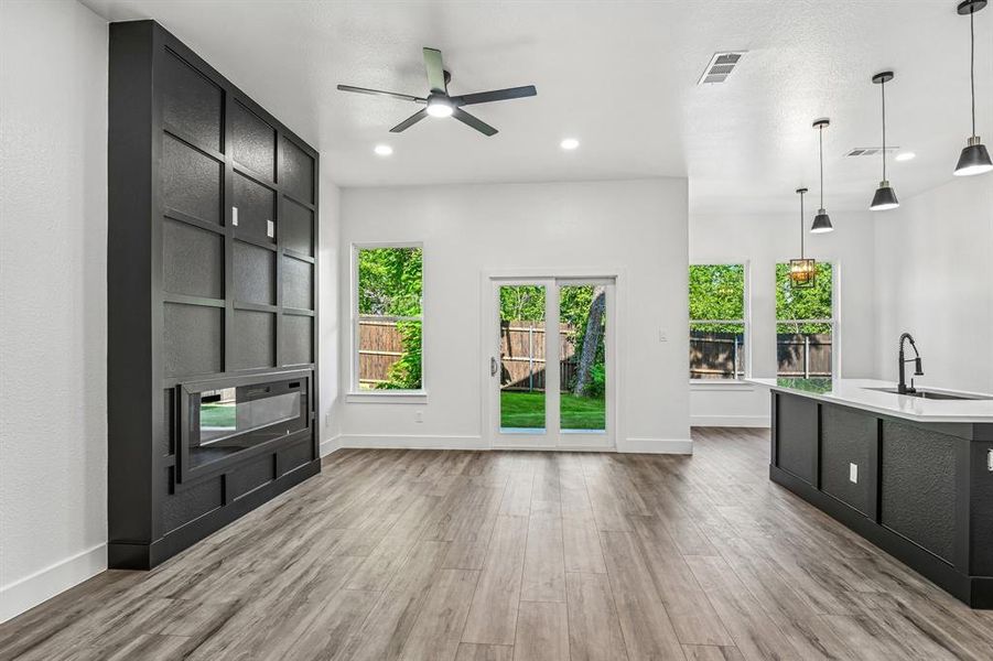 Open-concept living area featuring wood-finish flooring, a contemporary ceiling fan, and recessed lighting