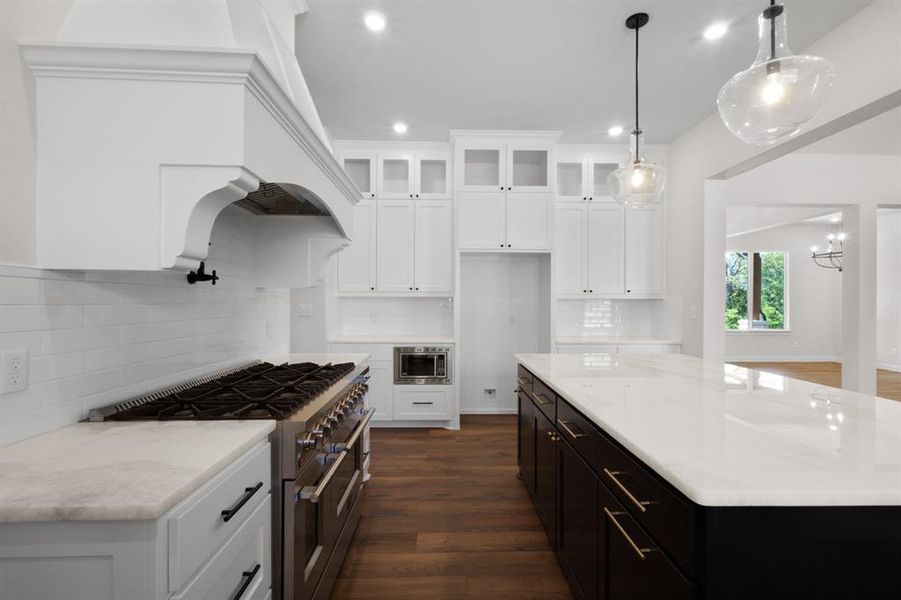 Kitchen featuring tasteful backsplash, range with two ovens, white cabinets, and recessed lighting