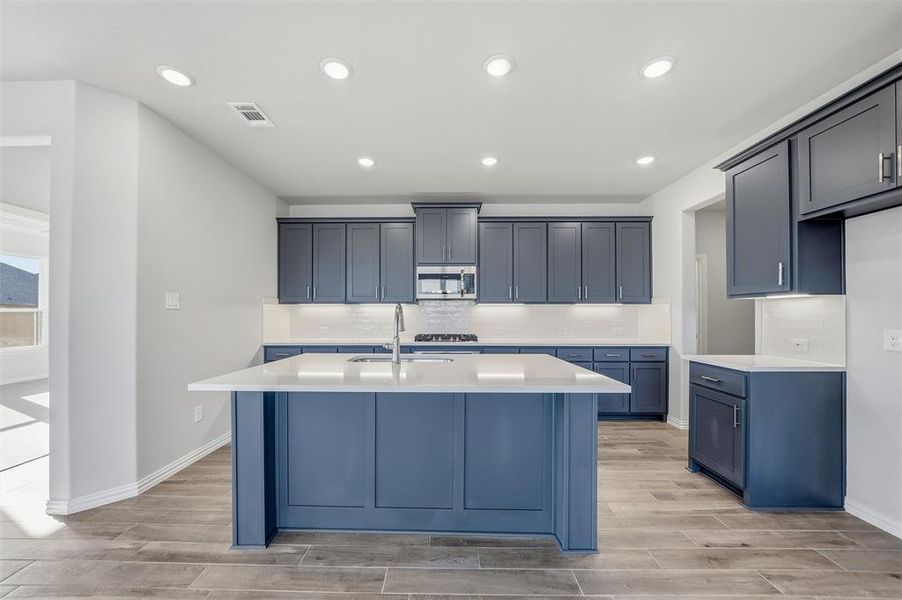 Kitchen featuring a center island with sink, tasteful backsplash, recessed lighting, wood finish floors, and appliances with stainless steel finishes Kitchen featuring a center island with sink, tasteful backsplash, recessed lighting, wood finish floors, and appliances with stainless steel finishes