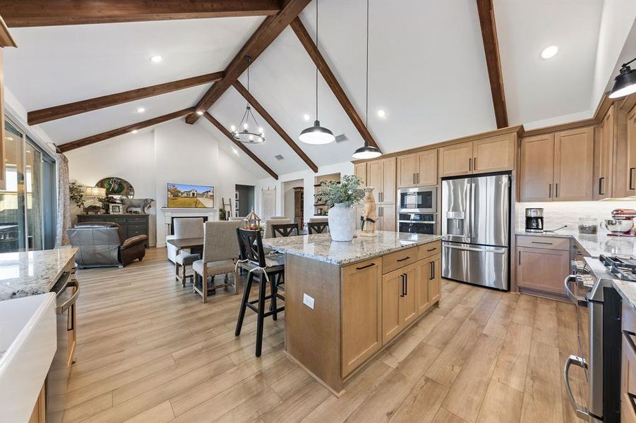 Kitchen with gas cooktop, double ovens, stainless appliances, large island, and abundant storage.