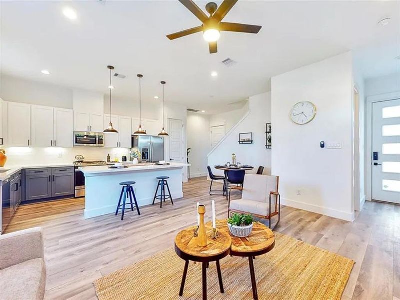 The kitchen is bright and airy, with large windows that let in plenty of natural light. The room is decorated with a few plants and other decorative items, creating a warm and inviting atmosphere. The kitchen is well-equipped, with a microwave, oven, and dishwasher. The overall design of the kitchen is modern and minimalist, with a focus on functionality and clean lines.