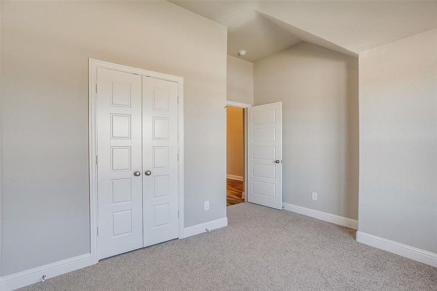 Unfurnished bedroom with vaulted ceiling, a closet, and light carpet Unfurnished bedroom with vaulted ceiling, a closet, and light carpet