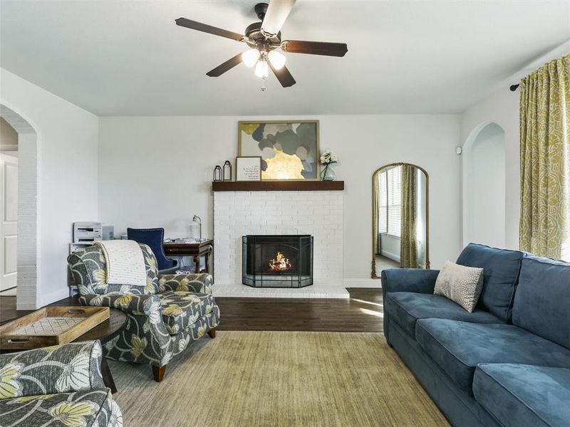 Living room featuring ceiling fan, a fireplace, and hardwood / wood-style flooring