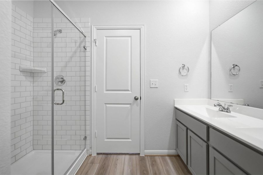 Bathroom with a stall shower, double vanity, and light wood-style floors