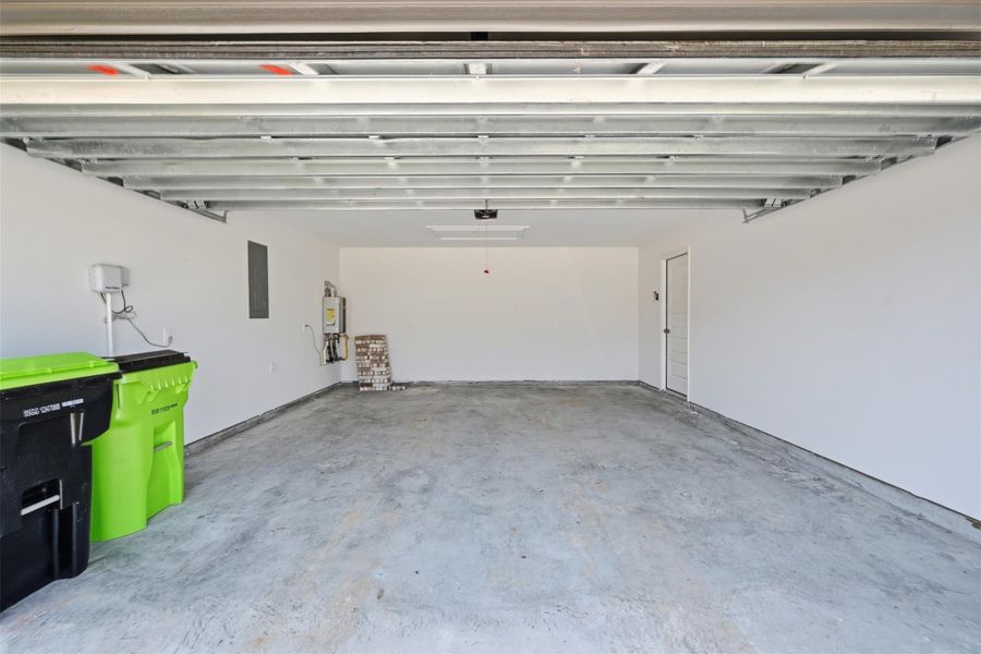 Spacious two-car garage with clean white walls, concrete flooring, and ample storage space, ideal for vehicles or workshop needs.