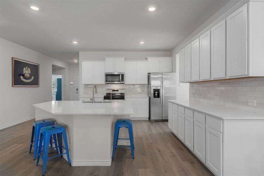 Kitchen with a breakfast bar, stainless steel appliances, a sink, and wood finished floors