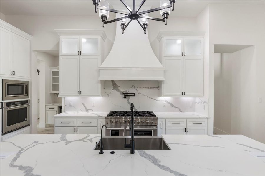 The kitchen has such great appeal with quartz countertops, a large black chandelier over the island, matching black faucet and hardware, undermount lights, and upper cabinets with lights. The kitchen has such great appeal with quartz countertops, a large black chandelier over the island, matching black faucet and hardware, undermount lights, and upper cabinets with lights.