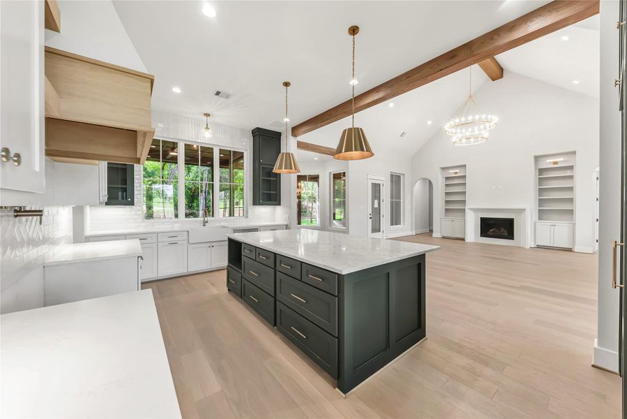 Kitchen with beam ceiling, high vaulted ceiling, white cabinets, light wood-type flooring, and recessed lighting