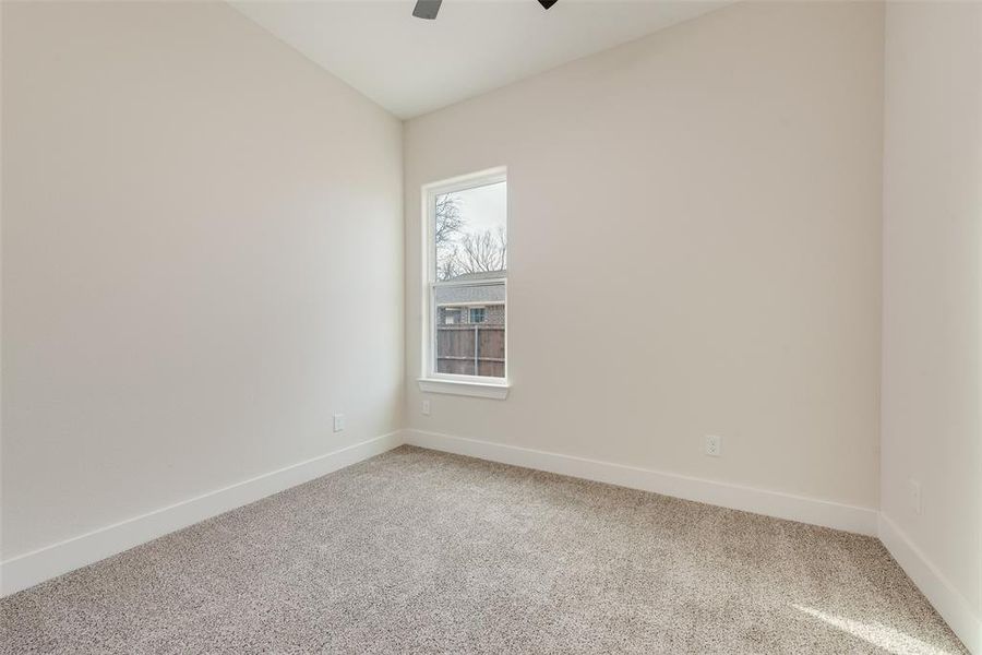 Carpeted spare room featuring baseboards and ceiling fan