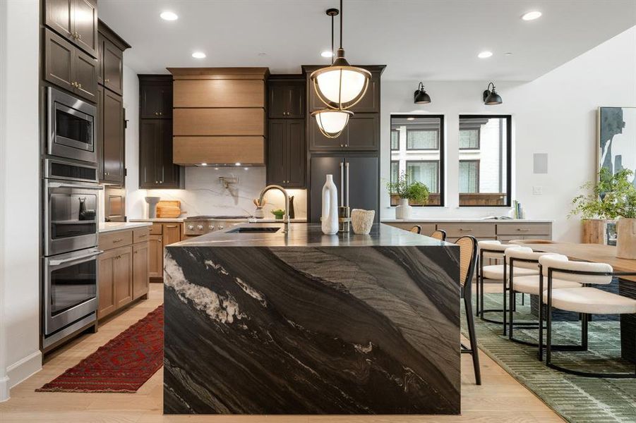 Kitchen featuring decorative backsplash, appliances with stainless steel finishes, recessed lighting, light wood-style flooring, and hanging light fixtures Kitchen featuring decorative backsplash, appliances with stainless steel finishes, recessed lighting, light wood-style flooring, and hanging light fixtures