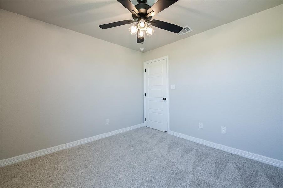 Carpeted spare room featuring baseboards and a ceiling fan