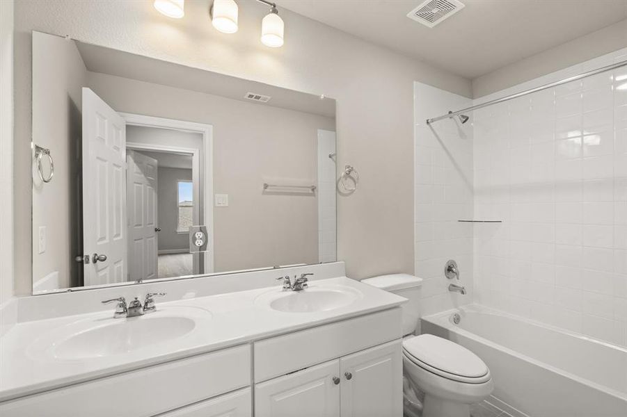 The secondary bath features tile flooring, white cabinetry and light countertops and a shower/tub combo. Perfect for accommodating any visiting family and friends.