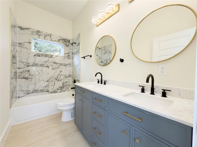 Bathroom featuring double vanity, shower / tub combination, and light wood-type flooring