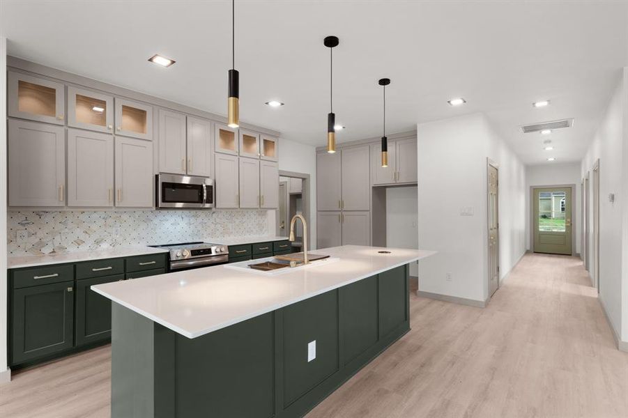 Kitchen featuring a sink, light wood finished floors, appliances with stainless steel finishes, and green cabinets