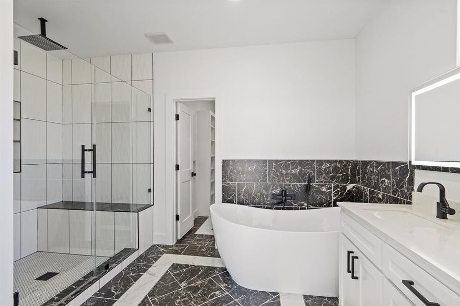 Bathroom featuring vanity, tile walls, and plus walk in shower