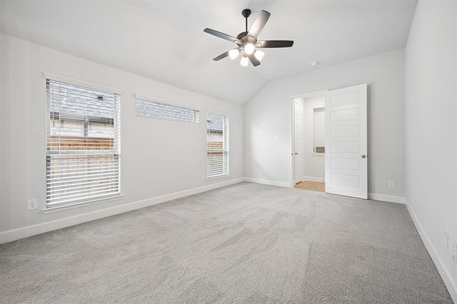 Primary bedroom featuring carpet flooring, multiple windows, a ceiling fan with integrated lighting