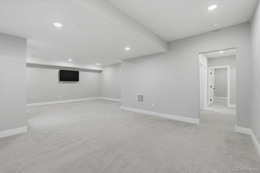 View of the family room from the stairs, toward the back hallway leading to the bedrooms and third bath.