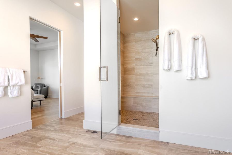 The rejuvenating private shower room features floor-to-ceiling tile, a built-in bench, two shower heads and a frameless glass entry.