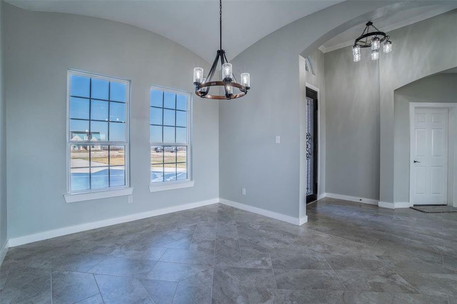 Unfurnished dining area with a chandelier, vaulted ceiling, and arched walkways Unfurnished dining area with a chandelier, vaulted ceiling, and arched walkways