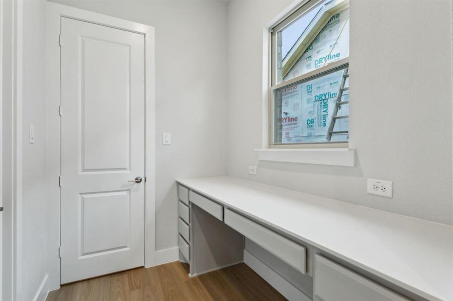 Unfurnished office featuring wood finished floors and built in desk