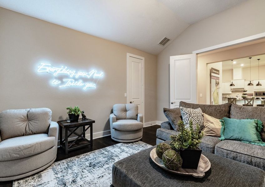 Media room with neon sign, sofa and chairs.