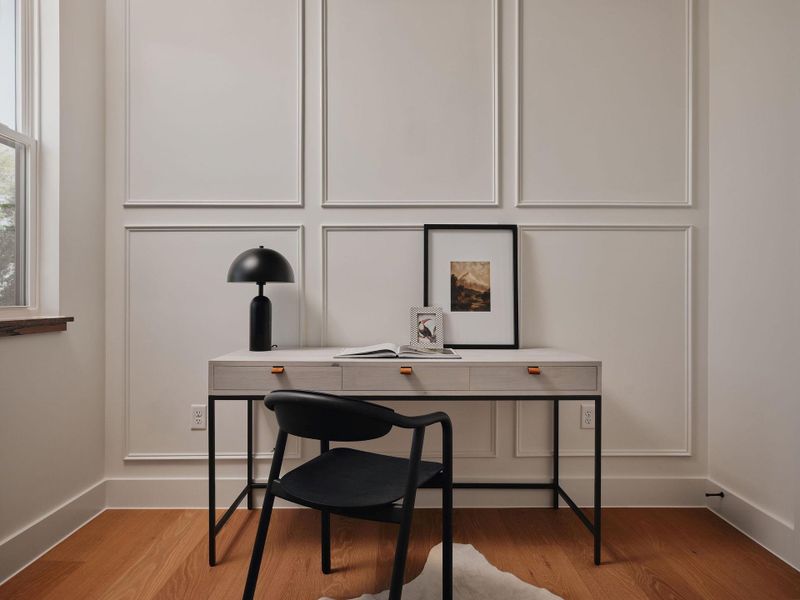 Office area with a decorative wall and light wood finished floors