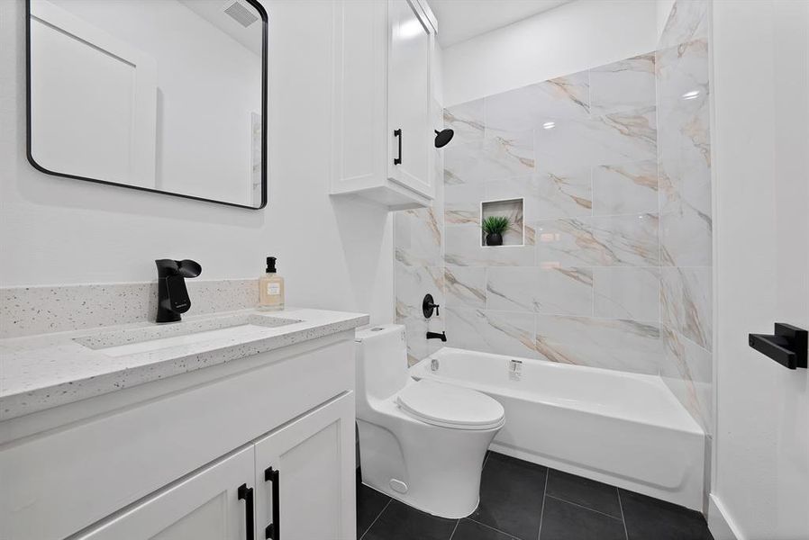 Bathroom featuring a white vanity with a speckled countertop, a rectangular undermount sink, and matte black fixtures