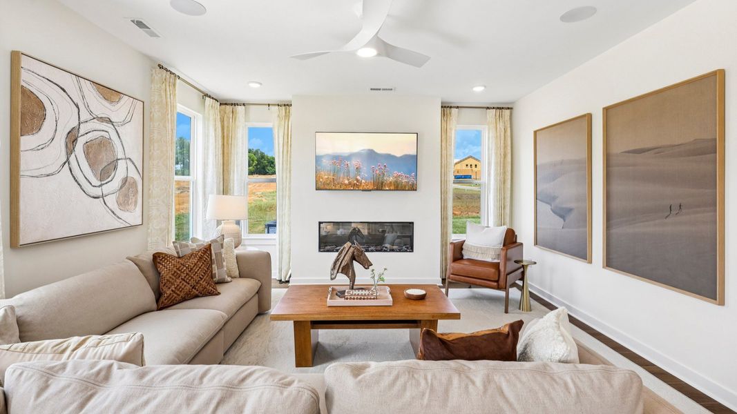 Gathering room with ceiling fan, hard surface flooring, fireplace, and natural lighting from windows Gathering room with ceiling fan, hard surface flooring, fireplace, and natural lighting from windows