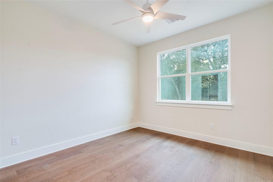 Spare room with light wood finished floors and a ceiling fan