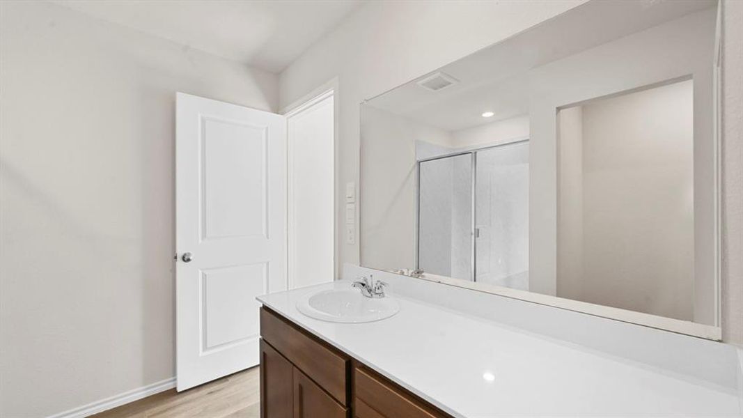 Full bath with vanity, a shower stall, and light wood-style floors