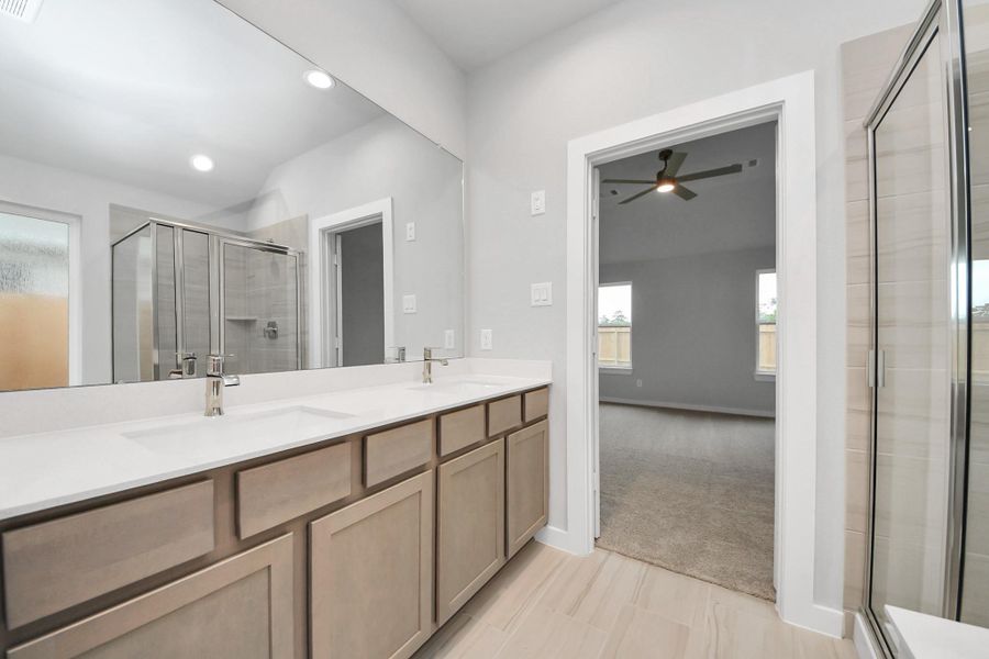 Elevate your daily routine at the elegant vanity, now equipped with double sinks, light countertops, modern hardware, and beautiful recessed lights. Sample photo of completed home with similar floor plan. Actual colors and selections may vary.