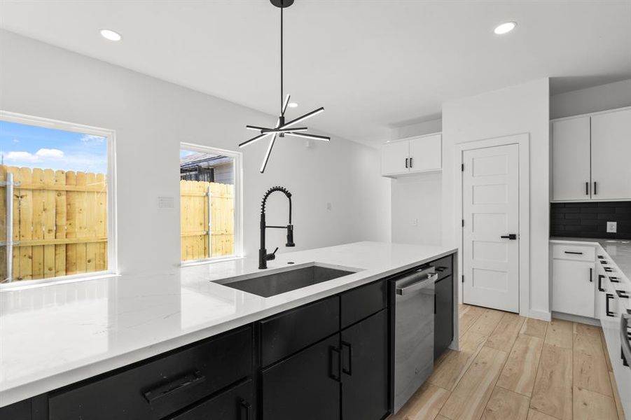 Kitchen featuring a sink, decorative backsplash, white cabinets, and stainless steel dishwasher