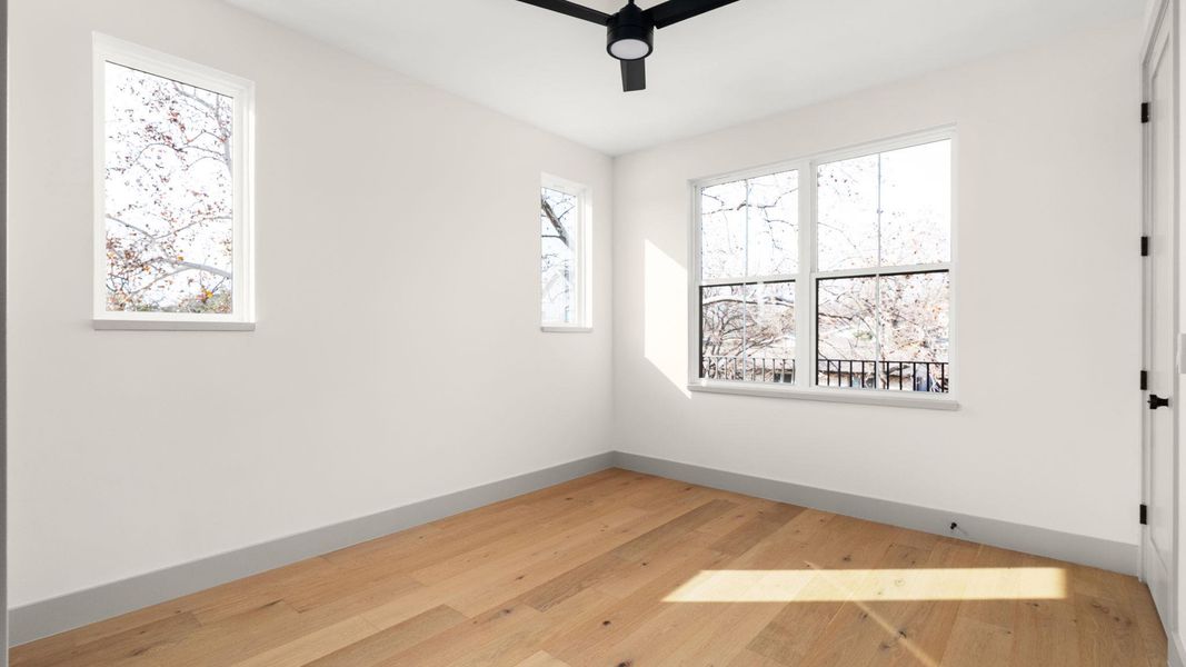 Spare room featuring light wood-type flooring, plenty of natural light, and ceiling fan