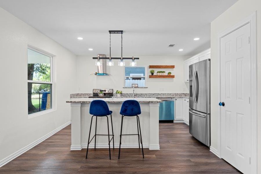 Kitchen featuring dark wood finished floors, stainless steel refrigerator with ice dispenser, a center island, white cabinets, and recessed lighting Kitchen featuring dark wood finished floors, stainless steel refrigerator with ice dispenser, a center island, white cabinets, and recessed lighting