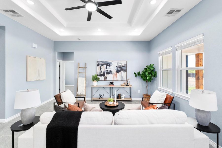 Carpeted living room with a tray ceiling, a ceiling fan, and recessed lighting Carpeted living room with a tray ceiling, a ceiling fan, and recessed lighting