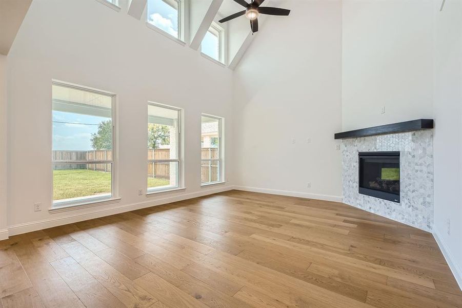 Unfurnished living room with light hardwood / wood-style floors, ceiling fan, and a towering ceiling