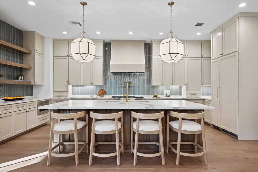 This kitchen features a spacious island with a wood finish, elegant pendant lighting, and ample cabinetry for storage. The design includes a modern backsplash, high-end appliances, and a bright, open layout. Perfect for cooking and entertaining. This kitchen features a spacious island with a wood finish, elegant pendant lighting, and ample cabinetry for storage. The design includes a modern backsplash, high-end appliances, and a bright, open layout. Perfect for cooking and entertaining.