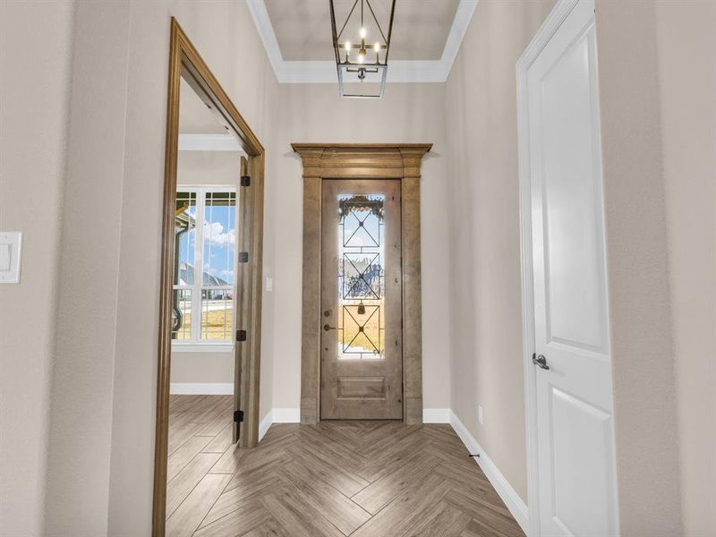 Entrance foyer featuring parquet flooring, an inviting chandelier, and ornamental molding