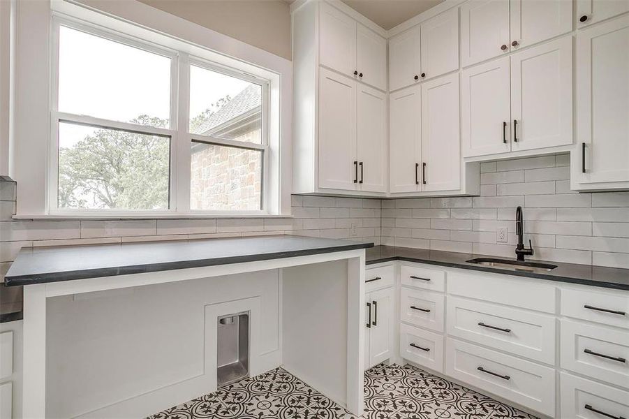 Kitchen featuring a sink, white cabinets, and dark countertops Kitchen featuring a sink, white cabinets, and dark countertops