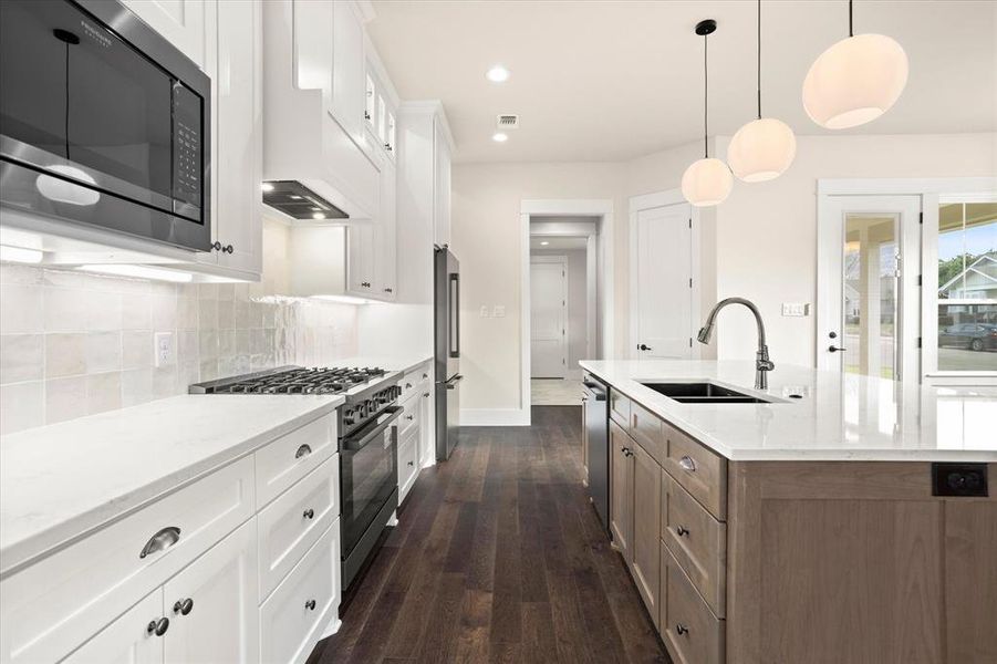 Kitchen featuring a kitchen island with sink, stainless steel appliances, dark hardwood / wood-style flooring, sink, and white cabinets