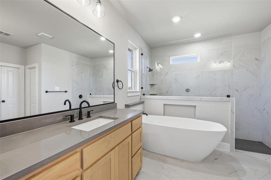 Full bathroom with light marble finish floors, a marble finish shower, vanity, a freestanding bath, and recessed lighting