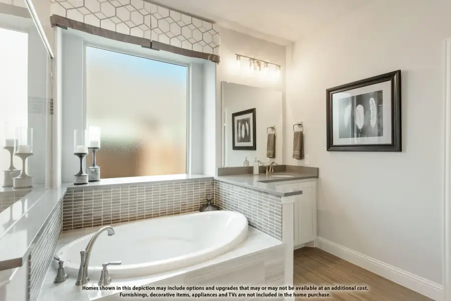 Master bathroom with soaking tub, tile surround, dual vanity, and large window with frosted glass